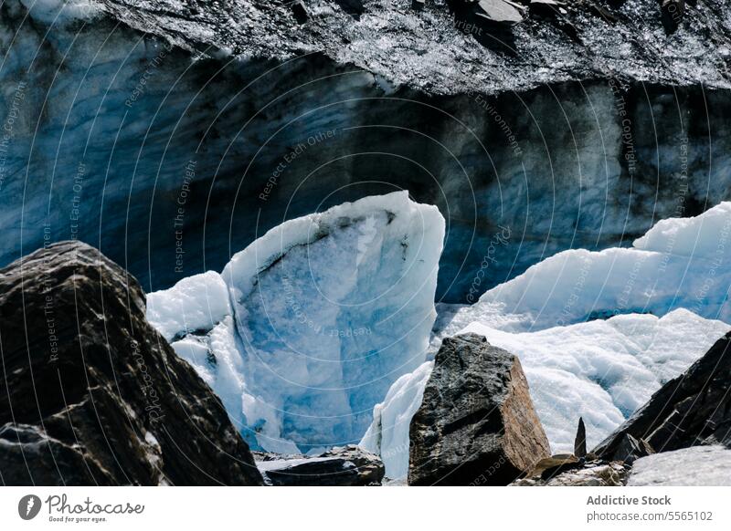 Glacier close-up with rocks glacier ice formation sunlight texture blue cold nature melt environment landscape winter snowy mountain freeze water erosion