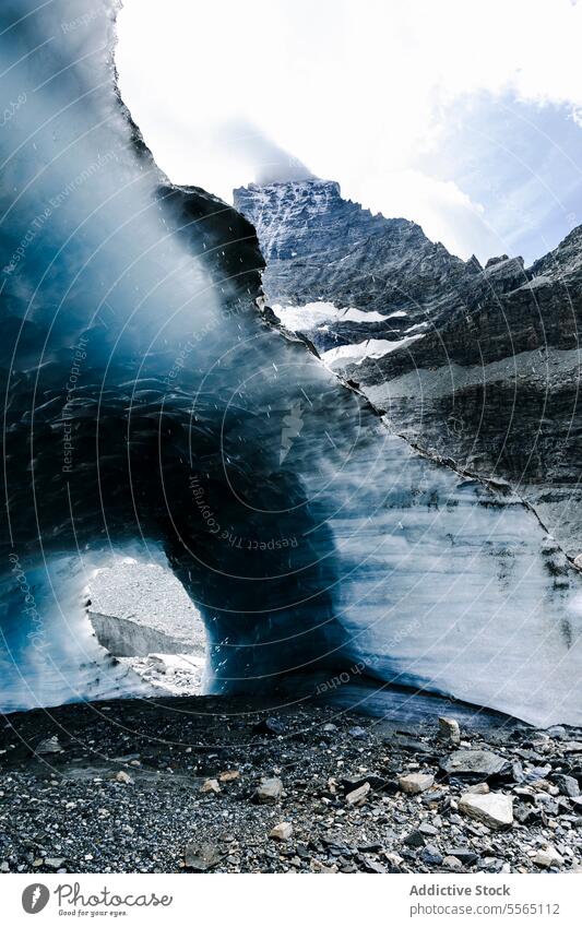 Arched glacier in rocky landscape arch terrain sky cloudy expansive nature ice blue white mountain environment beauty formation winter erosion outdoor cold