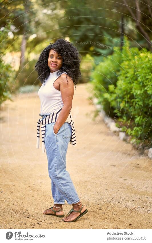 Radiant woman enjoying nature's beauty garden smile curly hair portrait African-American outdoors summer day fashion tree cheerful emotion green real people