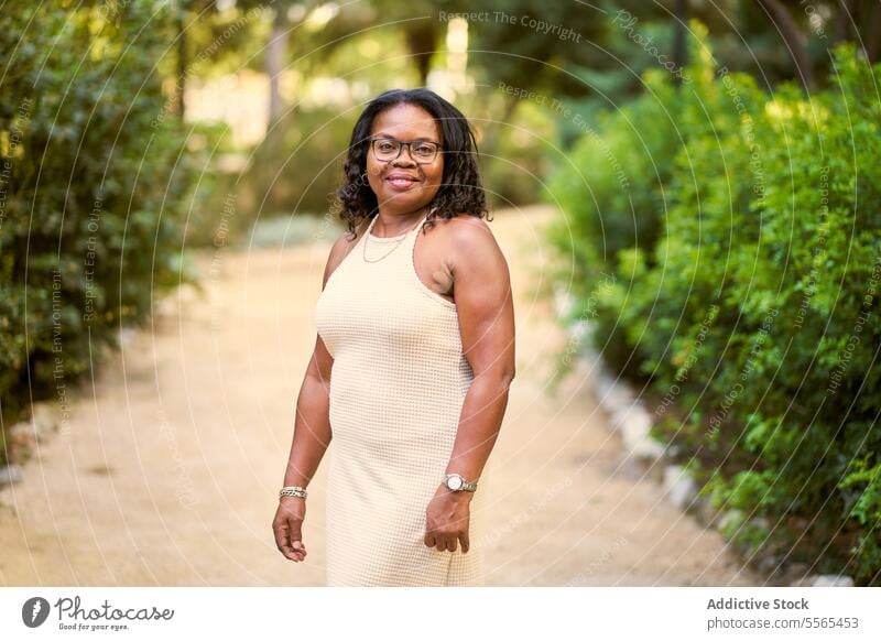 Radiant woman enjoying nature's beauty garden smile curly hair portrait African-American outdoors summer day fashion tree cheerful emotion green real people