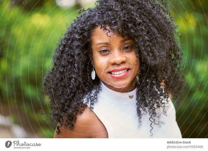 Radiant woman enjoying nature's beauty garden smile curly hair portrait African-American outdoors summer day fashion tree cheerful emotion green real people