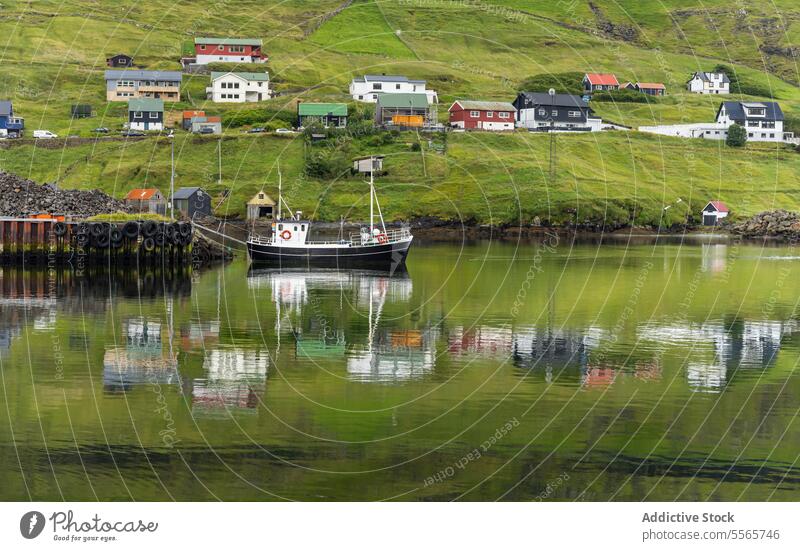 Boat floating in lake with houses on grassy shore settlement boat village building landscape coast nature trip island cottage yacht travel road trip