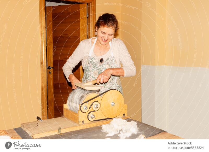 Title: Woman preparing wool with drum carder in bright room woman preparation spinning hand-operated smile work textile fiber craft equipment tool manual