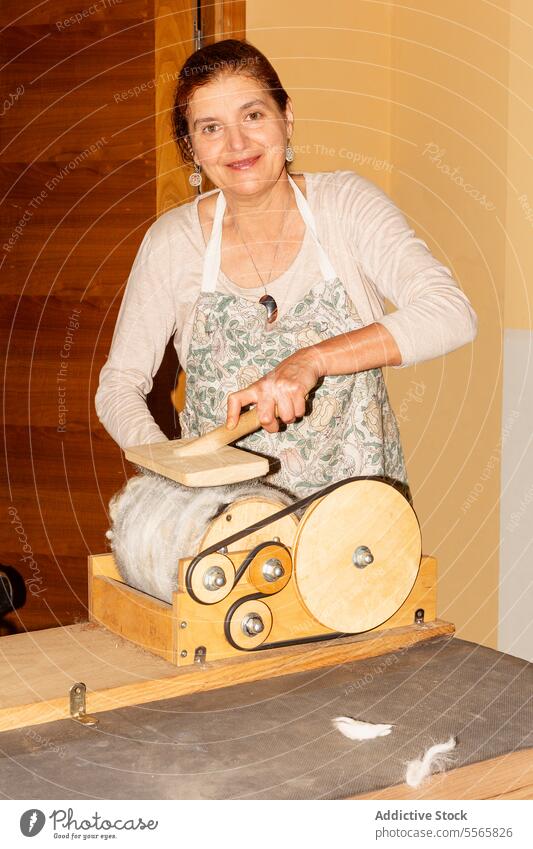 Title: Woman preparing wool with drum carder in bright room woman preparation spinning hand-operated smile work textile fiber craft equipment tool manual