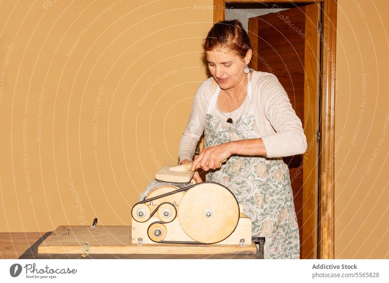 Title: Woman preparing wool with drum carder in bright room woman preparation spinning hand-operated smile work textile fiber craft equipment tool manual