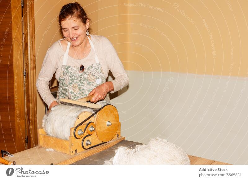 Title: Woman preparing wool with drum carder in bright room woman preparation spinning hand-operated smile work textile fiber craft equipment tool manual