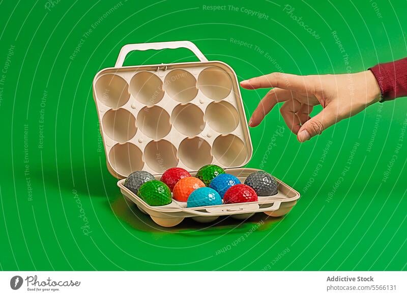 Crop hand demonstration with colorful golf balls with plastic box round field container lawn multicolored shiny ground sport game play show sphere object bright