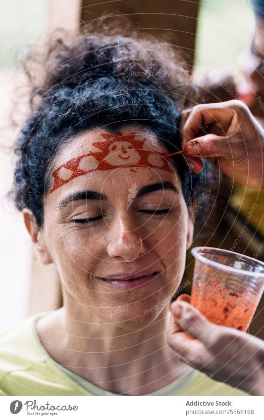 Smiling woman with closed eyes painting on face eyes closed tradition smile happy art middle age curly hair positive forehead glad optimist pleasant casual