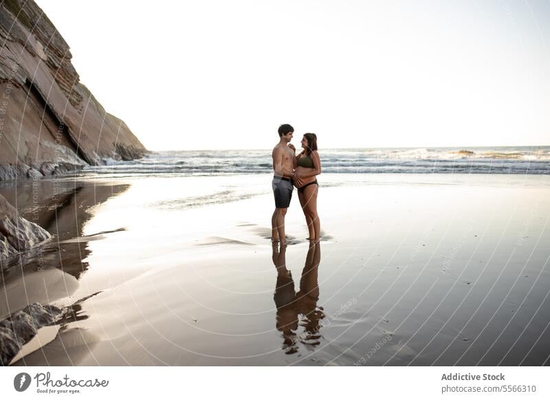 Smiling man touching belly of pregnant woman on seashore couple sunset tummy together love pregnancy evening tender summer relationship harmony seaside sundown