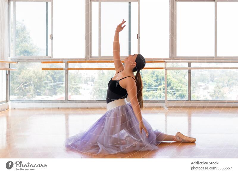 Contemplative moment in ballet studio dancer leotard black purple skirt window sunlight city floor focus contemplate pointe shoe posture grace serenity backdrop