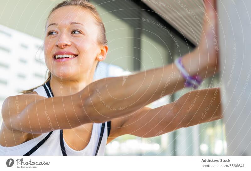 A woman in a white tank top and pink shorts stretching fitness active exercise workout sport health wellness athlete flexibility gym active wear athletic street