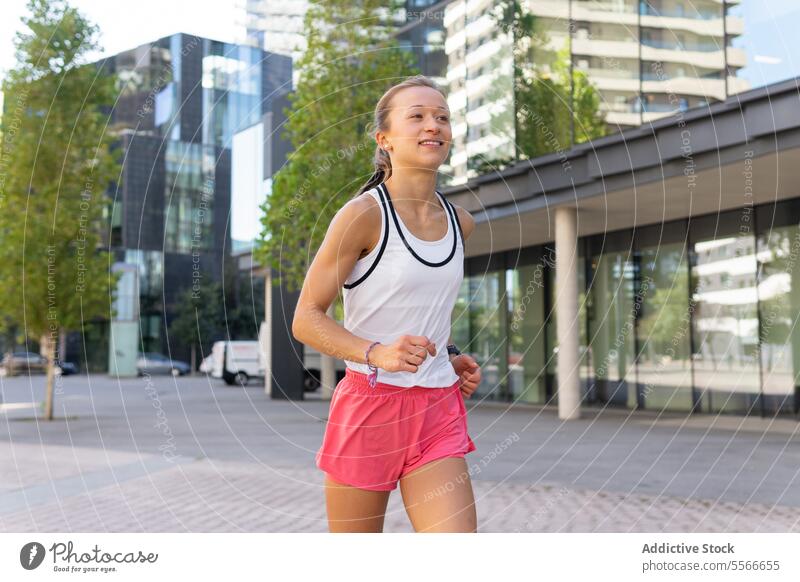 A woman running down a sidewalk in a city urban fitness sport active metropolitan lifestyle jungle exercise pavement jog runner downtown activity health