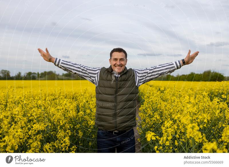 Man's joyful embrace of nature in yellow field man arms mature spread flower exuberance celebration outdoor happiness freedom meadow portrait rap caucasian