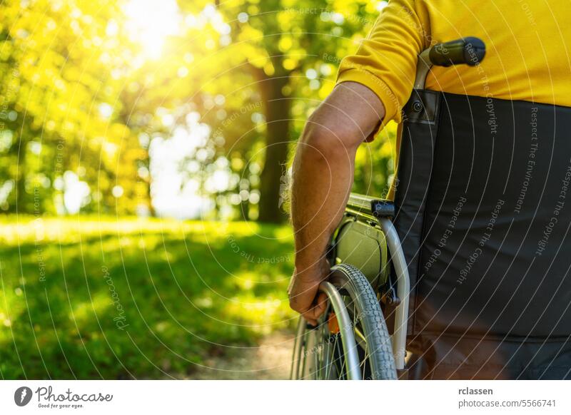 Close up of senior handicapped man sit in wheelchair during walk in park with copyspace, mature disabled old man grandfather in invalid carriage or wheel chair, elderly disability concept image