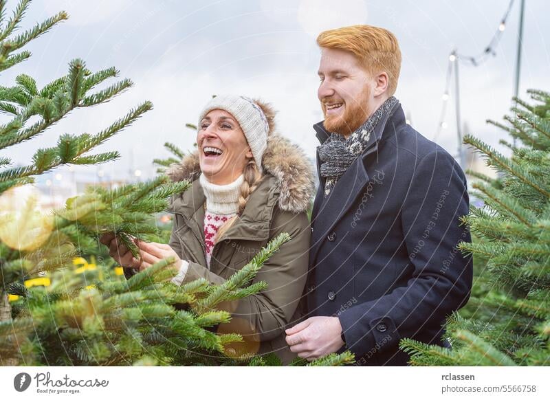 happy couple choosing christmas tree at street market surprised family skeptical redhead tradition choice smile man love couple purchase farm pine tree norway