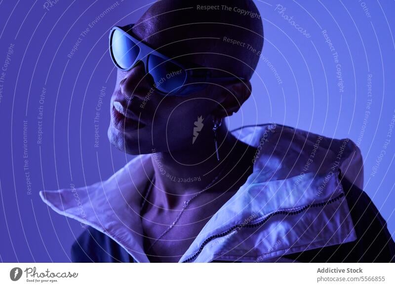 Bald male model with sunglasses posing on blue background man young stylish bald confident casual attire looking piercing emotionless outfit standing