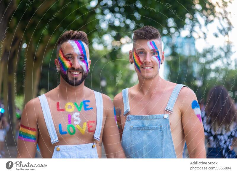 Painted men celebrating LGBT pride outdoors man paint smile denim face celebration colorful street festival love LGBTQ unity equality joy happiness event