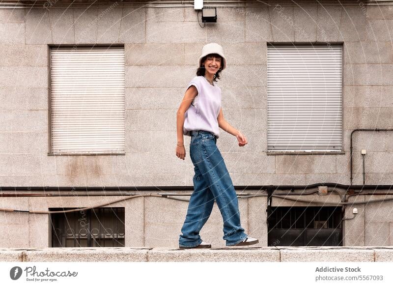 Young woman walking on stone border in street personality confident style cool freedom female carefree accessory individuality gaze self assured stare young