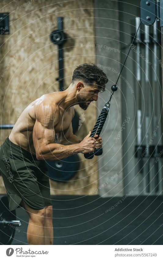 Resistance training intensity man gym resistance rope shirtless green shorts torso focus stretch muscle hand urban intense chiseled workout fitness strength