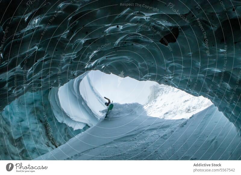 Skier with ski poles exploring cave on snow mountain unrecognizable skier walking snowy vacation exploration person hiking winter explorer adventure lifestyle