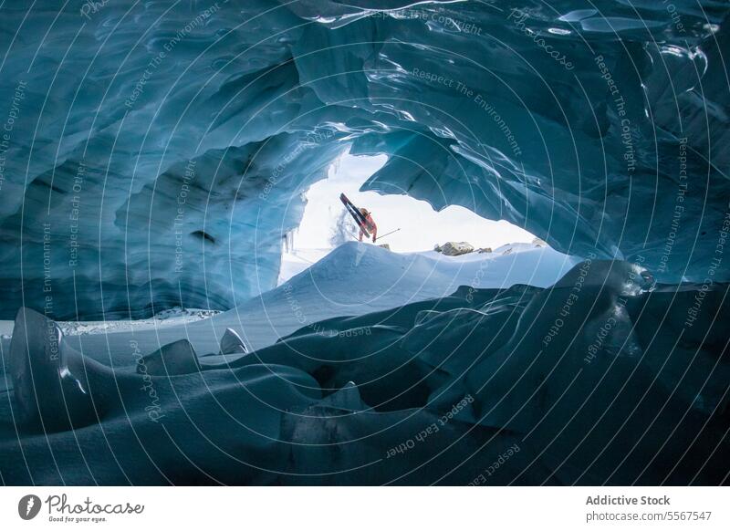 Skier with ski poles exploring cave on snow mountain unrecognizable skier walking snowy vacation exploration person hiking winter tranquil explorer adventure