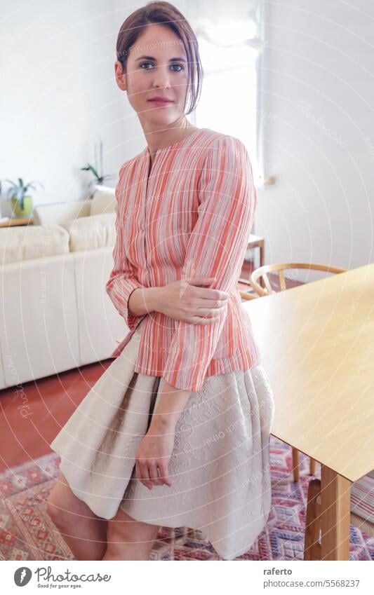 Pretty fashion model wearing pink shirt and beige skirt while standing at home person woman pretty beauty lifestyle female young lady portrait girl beautiful