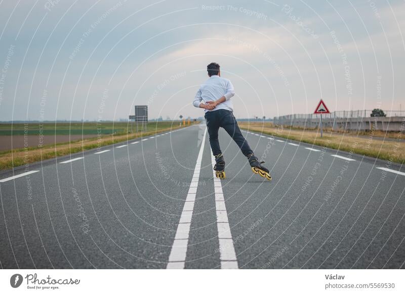 Handsome young athlete rollerblades on Dutch roads to improve endurance and fitness. A young man trains stability and enjoying the fresh air. Sport lifestyle