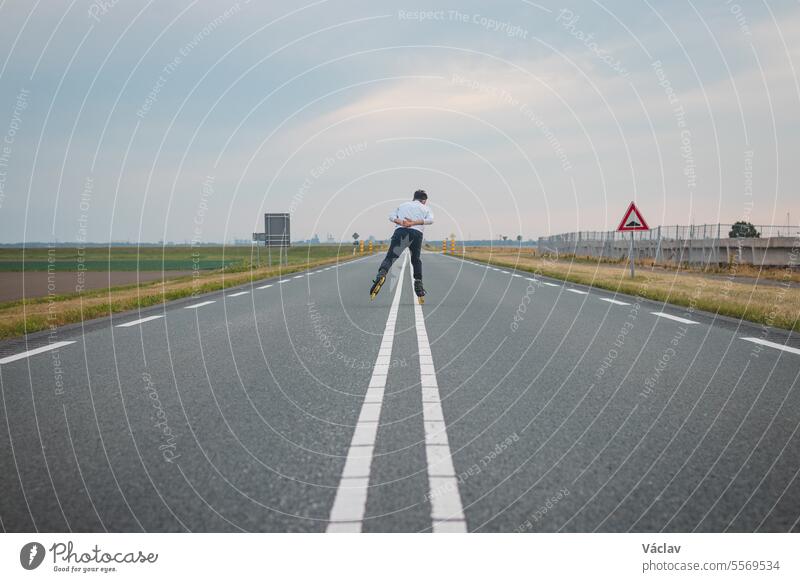 Handsome young athlete rollerblades on Dutch roads to improve endurance and fitness. A young man trains stability and enjoying the fresh air roller skates