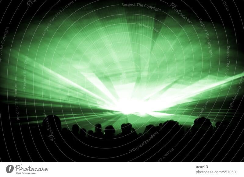 Green laser show nightlife club stage with party people crowd. Luxury entertainment with audience silhouettes in nightclub event, festival or New Years Eve. Beams and rays shining colorful lights