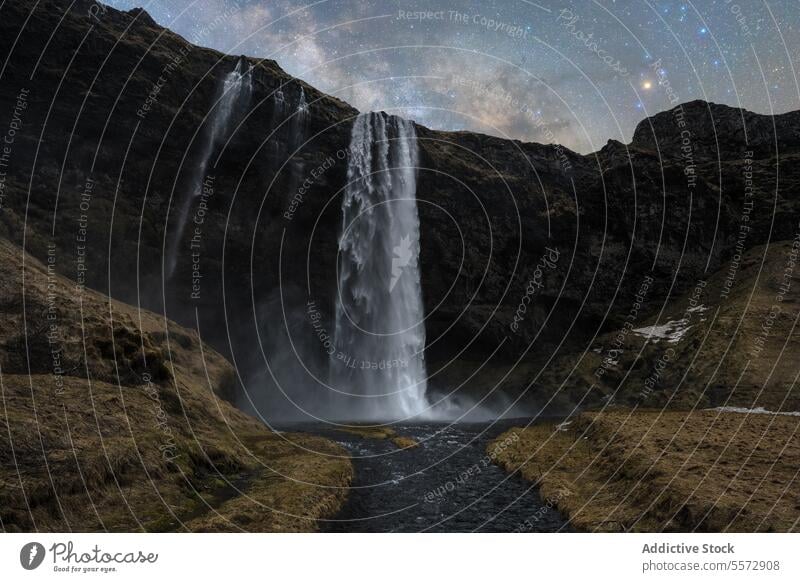 Cascading waterfalls under starlit sky in Iceland night cascade river cliff dark rocky serene beauty majestic celestial astral outdoors wilderness landscape