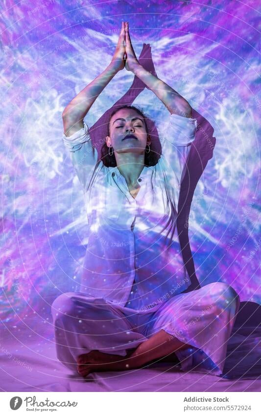 Woman meditating amidst galactic ambiance for spiritual solace woman meditation galaxy mental rejuvenation posture peace universe aura emotion balance