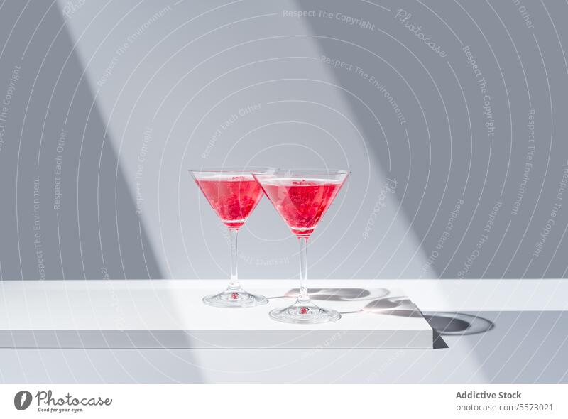 Elegant pomegranate cocktails presentation glass red garnish backdrop shadow gray vibrant beverage drink elegant decorative topping silhouette minimalistic