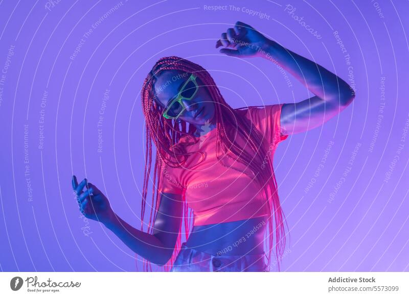 Woman with orange braids standing in neon lights woman young portrait metaverse afro braids abstract serious confident individuality appearance sunglasses