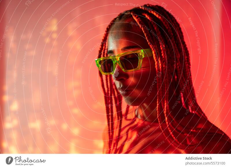 Woman with orange braids standing in neon lights woman young portrait metaverse afro braids abstract serious confident individuality appearance sunglasses