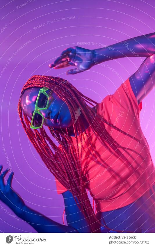 Woman with orange braids standing in neon lights woman young portrait metaverse afro braids abstract serious confident individuality appearance sunglasses