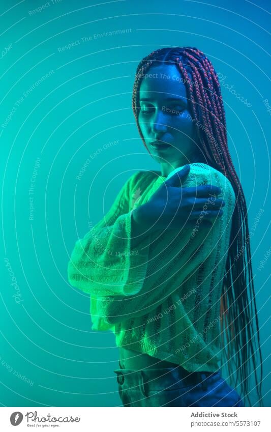 Thoughtful sad woman standing in green light young braids contemplate serious blue neon glowing dreaming thinking pensive expression wonder imagine lonely