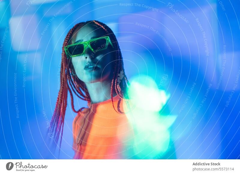 Woman with orange braids standing in neon lights woman young portrait metaverse afro braids abstract serious confident individuality appearance sunglasses