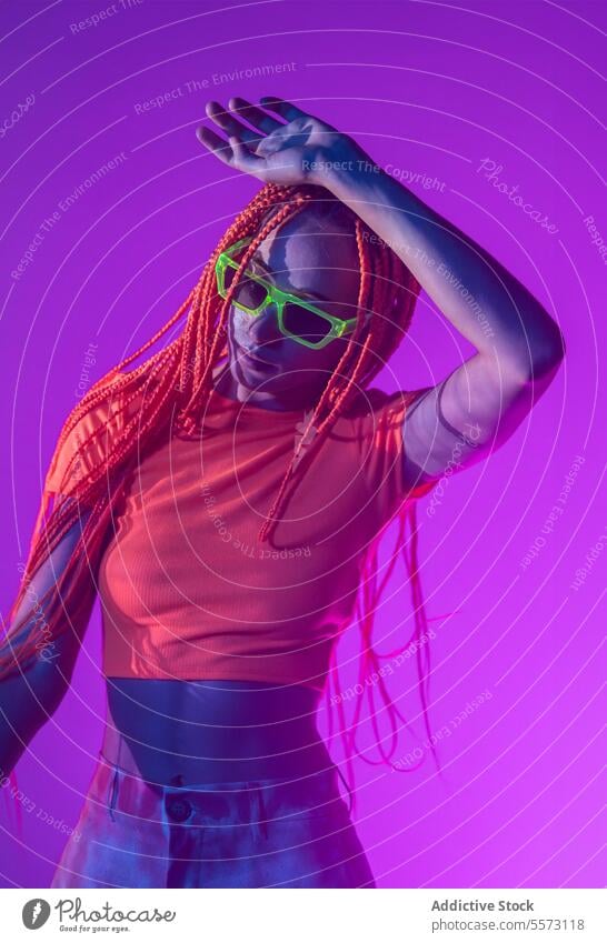 Woman with orange braids standing in neon lights woman young portrait metaverse afro braids abstract serious confident individuality appearance sunglasses