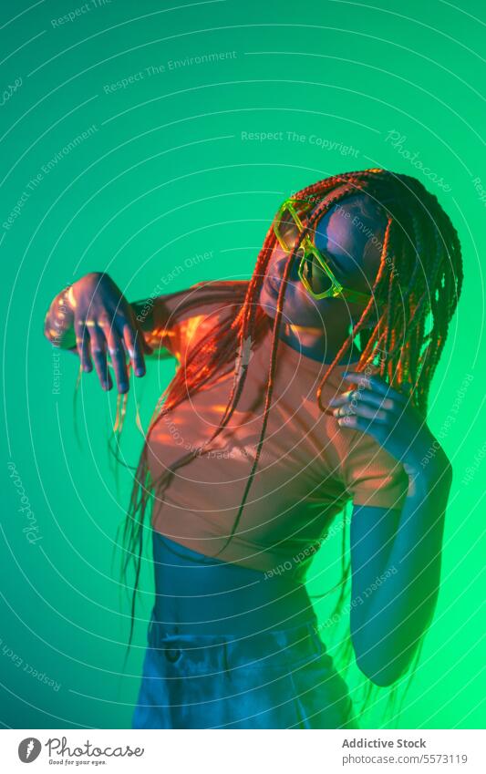 Woman with orange braids standing in neon lights woman young portrait metaverse afro braids abstract serious confident individuality appearance sunglasses