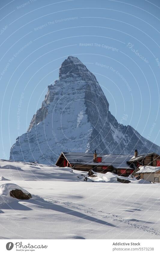 Alpine peak and cabins in snow mountain alpine winter house cottage landscape nature outdoors cold traditional wooden blue sky elevation high frozen tourism