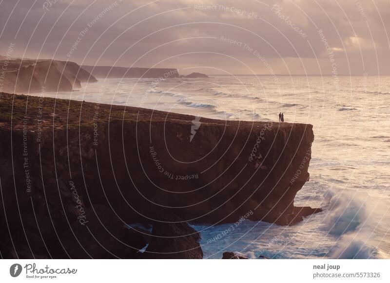 Couple on the cliff of a steep coast in the evening light - long shot Landscape Nature Romance togetherness Cliff Sunset Evening poetry Vacation & Travel