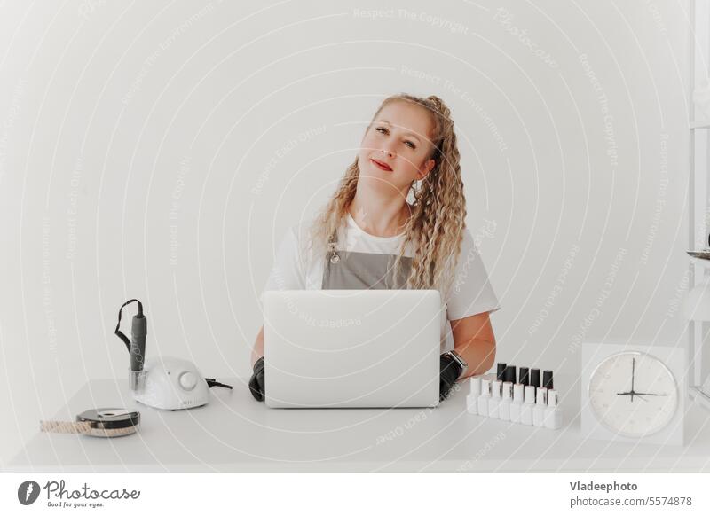 Woman Professional Manicurist at her Desk Works with a Laptop. Sign up for manicure Services, Freelancer Work Schedule salon nail manicurist laptop entry