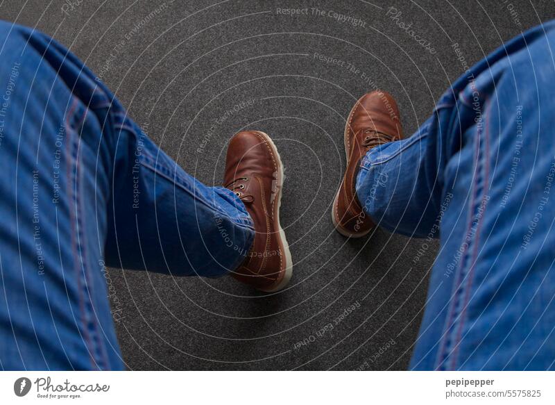 Man in jeans sits on a chair and looks down at his shoes middle-aged man sedentary Sit sitting.legs seated man Mid adult man Only one man Human being