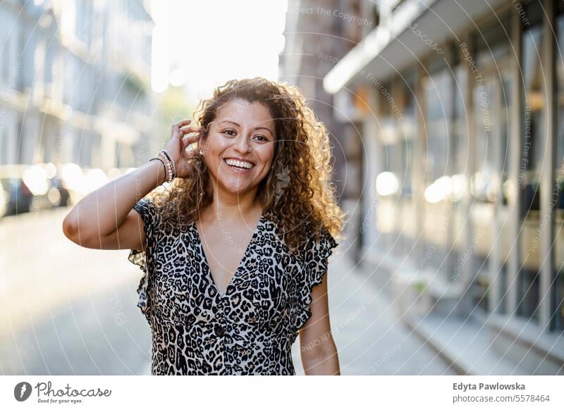 Portrait of a smiling young woman with curly hair in the city young adult street outside confidence enjoy laughing fun natural one person portrait expression