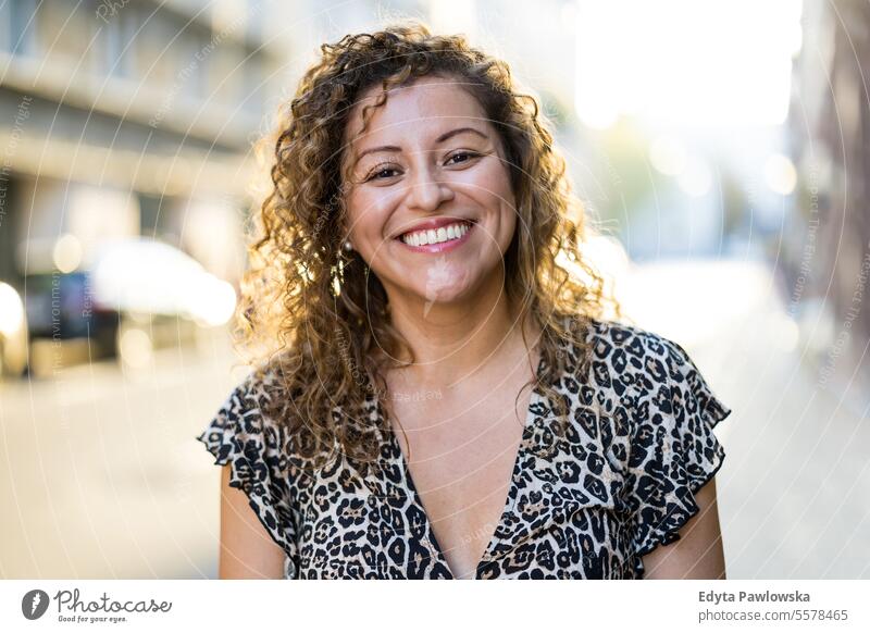 Portrait of a smiling young woman with curly hair in the city young adult street outside confidence enjoy laughing fun natural one person portrait expression