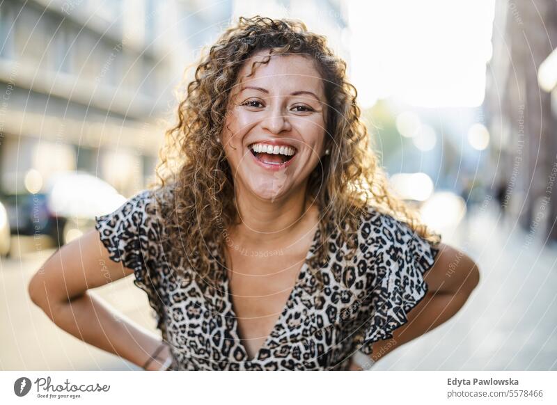 Portrait of a smiling young woman with curly hair in the city young adult street outside confidence enjoy laughing fun natural one person portrait expression