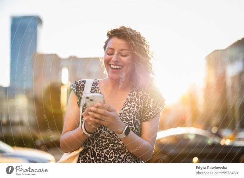 Portrait of a smiling young woman using mobile phone in the city young adult street outside confidence enjoy laughing fun natural one person portrait expression