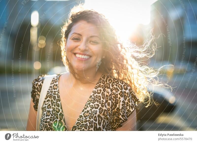 Portrait of a smiling young woman with curly hair in the city young adult street outside confidence enjoy laughing fun natural one person portrait expression