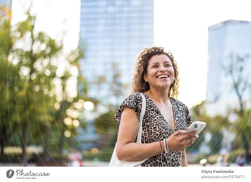 Portrait of a smiling young woman using mobile phone in the city young adult street outside confidence enjoy laughing fun natural one person portrait expression