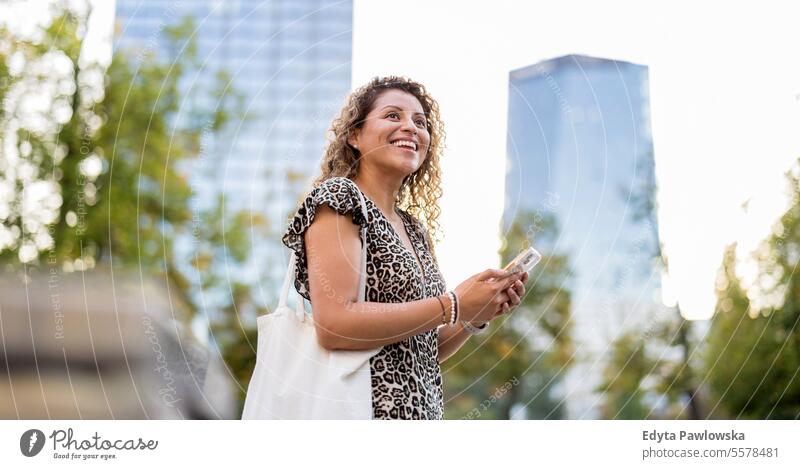 Portrait of a smiling young woman using mobile phone in the city young adult street outside confidence enjoy laughing fun natural one person portrait expression